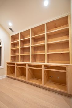 an empty room with wooden shelves and windows