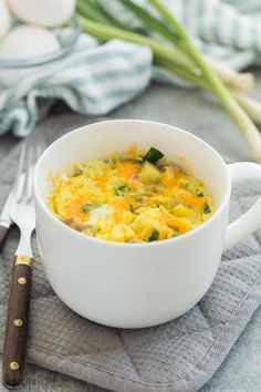 a white bowl filled with food on top of a table next to a knife and fork