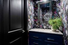 a bathroom with black and white wallpaper, blue cabinets and a plant on the counter