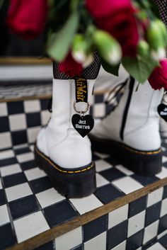 a pair of white boots sitting on top of a black and white checkered floor