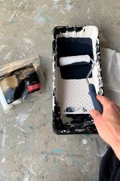 a person is painting a black and white object with paint rollers on the floor