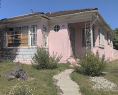 a pink house sitting on top of a lush green field