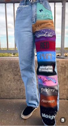 someone is standing with their skateboard on the side of a bridge and wearing jeans