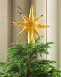 a yellow star decoration hanging from the side of a tree