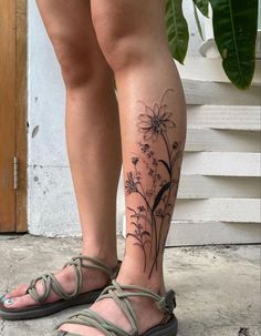 a woman's legs with tattoos on them and flowers in the bottom right leg