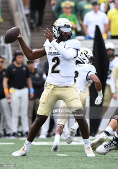 a football player throwing a ball on the field with other players in the stands watching