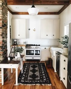 a kitchen with white cabinets and an area rug in front of the stove top oven