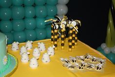 a table topped with lots of cake and decorations next to balloons in the shape of animals