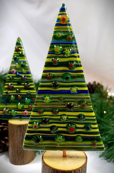 two glass christmas trees sitting next to each other on top of a tree stump in front of a white background