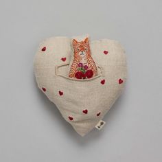 a heart shaped pillow with a cat in the pocket and hearts on it's side