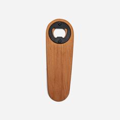 a wooden bottle opener with a black handle on a white background and an oval hole in the middle