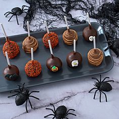 halloween cake pops with sprinkles and chocolate spider decorations on a black tray