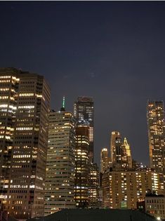 the city skyline is lit up at night, with skyscrapers in the foreground