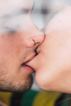 a man and woman kissing each other with their noses close together