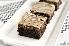 some brownies are sitting on a white plate and one is cut in half with frosting