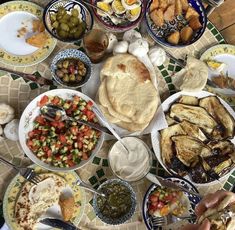 a table full of different types of food on plates and serving utensils in bowls