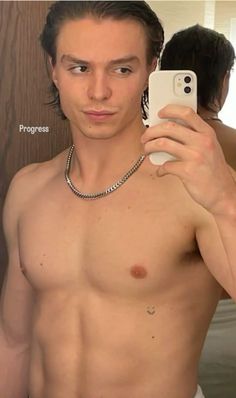 a shirtless man taking a selfie in front of a mirror with his cell phone