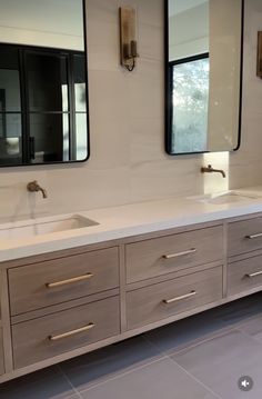 a bathroom with double sinks and mirrors on the wall above them is pictured in this image