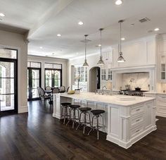 a large kitchen with white cabinets and wooden floors