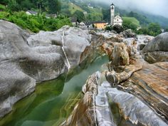 there is a small church on the top of this hill near some rocks and water