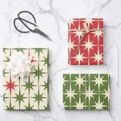 three wrapped presents on a marble surface with scissors and paper in the shape of stars