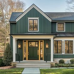 a green house with white trim and two large windows on the front door is shown