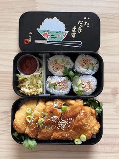 two black trays filled with food on top of a wooden table