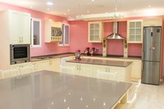 a kitchen with pink walls, white cabinets and an island countertop in the middle