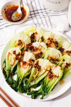 a white plate topped with cabbage covered in seasoning next to some chopsticks