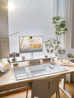 a desk with a computer monitor, keyboard and mouse on it next to a potted plant