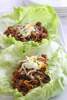 two lettuce cups filled with taco meat, cheese and sour cream sauce