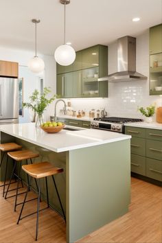 a kitchen with green cabinets and wooden stools in front of an island countertop