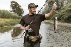 a man holding a fish while standing in the water