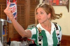 a woman in a green and white striped shirt is holding up a can of soda