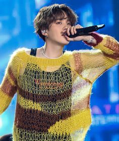 a male in a brown and white sweater holding a microphone