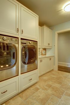 a washer and dryer in a large laundry room with beige tile flooring