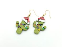 the earrings are decorated with green cactus and red santa's hat