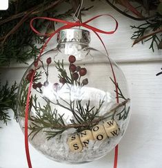 a snow globe ornament hanging from a christmas tree with the word snow written on it