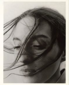 a black and white photo of a woman's face with her hair blowing in the wind