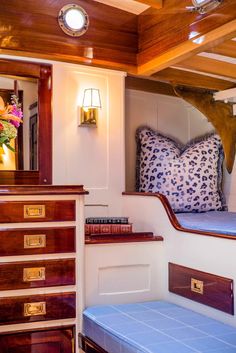 the inside of a boat with wooden furniture and blue cushions on it's sides