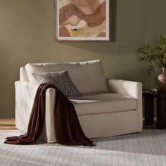 a living room with a white couch and brown blanket on the back of it's chair