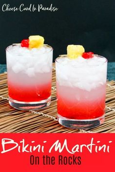 two glasses filled with drinks sitting on top of a bamboo mat next to each other