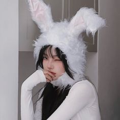 a woman in bunny ears is posing for the camera with her hand on her chin