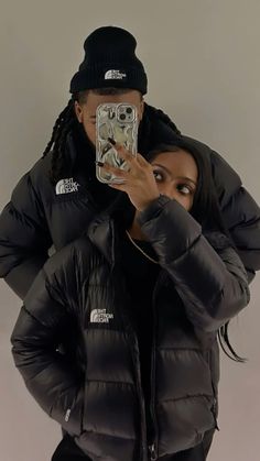 a woman taking a selfie in front of a mirror wearing a black puffer jacket