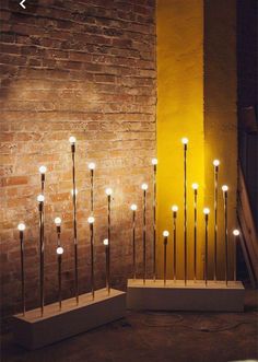 a bunch of candles that are sitting on some kind of stand in front of a brick wall