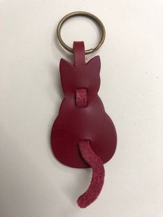 a red leather keychain with a cat shaped tag attached to it's side