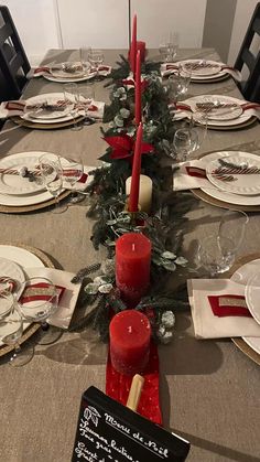 the table is set for christmas dinner with red candles