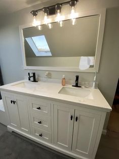 a bathroom vanity with two sinks and a large mirror on the wall above it,