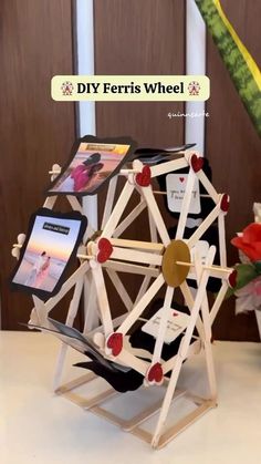 a ferris wheel made out of popsicle sticks and other items on a table with the words diy ferris wheel above it