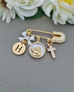 a gold and white cross, angel brooch pin with initial charm on the side